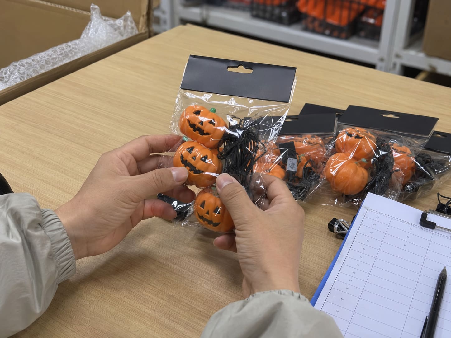 Quality inspection scene with Halloween product samples, packaging labels, and inspection documents laid out on a warehouse work table